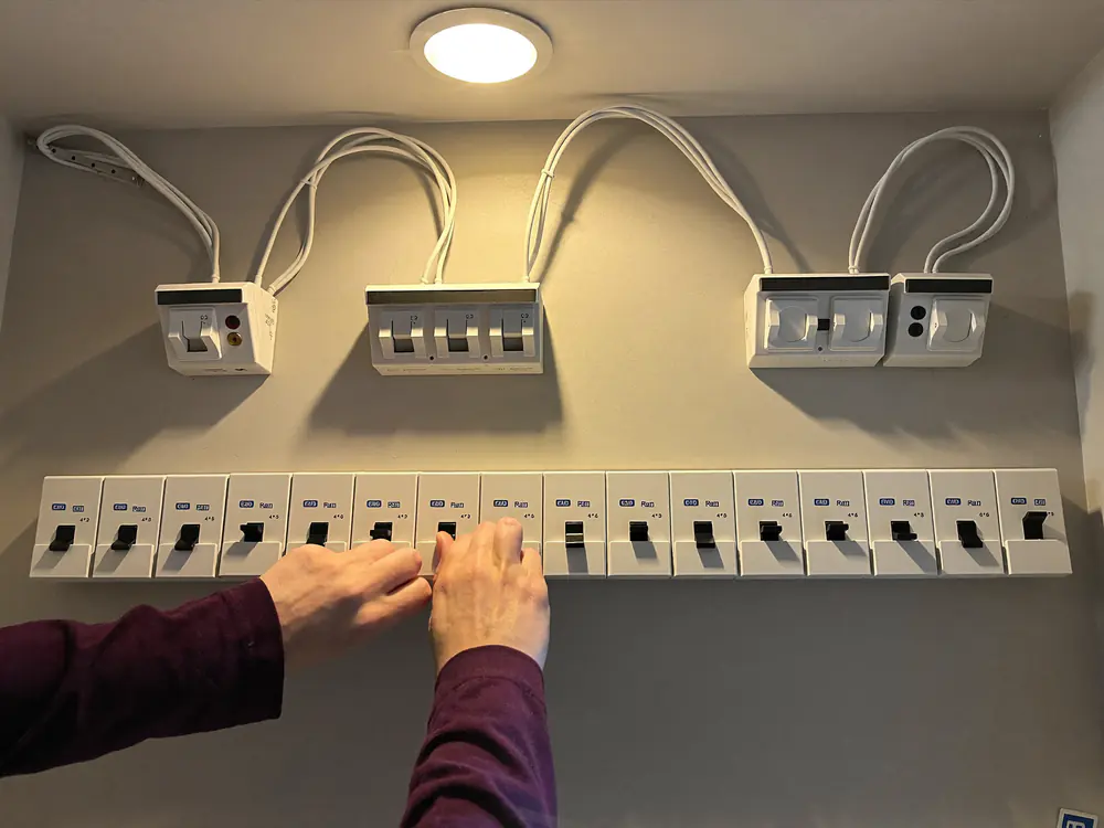 Handen schakelen een groep in op een nieuwe groepenkast met een lange rij automaten